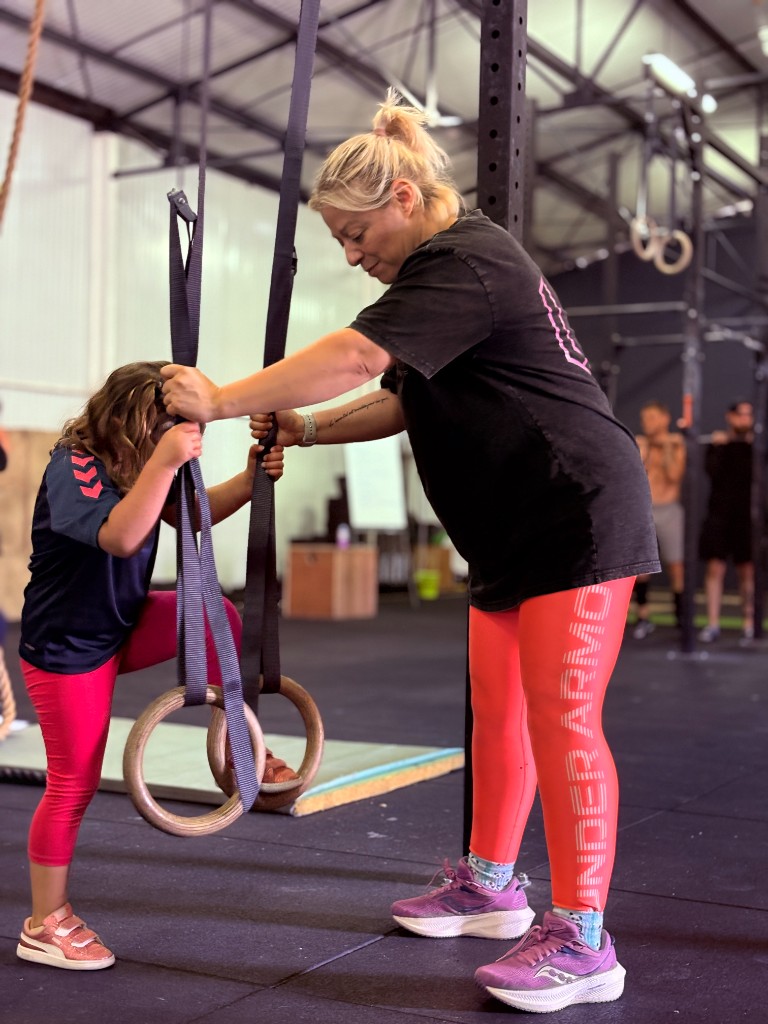 Un coach aide un enfant aux anneaux